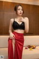 A woman in a black bra top and red skirt posing for a picture.