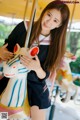 A woman in a school uniform holding a toy horse.