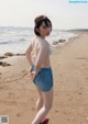 A woman standing on a beach next to the ocean.