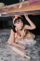 A woman laying on the floor under a table with a rolling pin.