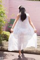 A woman in a white dress is walking on a wooden deck.