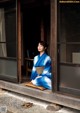 A woman in a blue kimono sitting on a window sill.