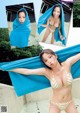 A woman in a bikini holding a blue towel over her head.