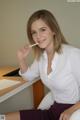 A woman sitting at a desk with a cigarette in her mouth.