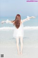 A woman standing on the beach with her arms outstretched.