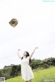 A woman in a white dress throwing a hat in the air.