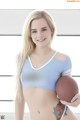 A woman in a blue sports bra top holding a football.